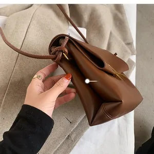 Detail view showing the multi-layered accordion side design of this brown leather square bag