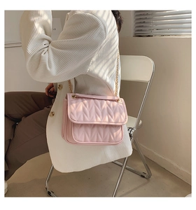 Detail of pink quilted leather shoulder bag with elegant gold chain strap and ruffles