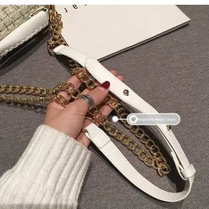 Détail de la bandoulière en chaîne dorée avec cuir blanc et perles sur un sac chic