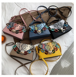 Detail view of colorful snake skin texture flaps and chunky resin chains on small handbags