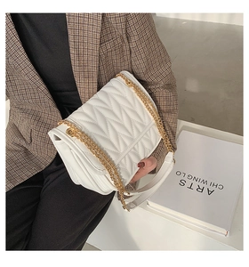 Close-up of white quilted chain bag with herringbone pattern and golden strap