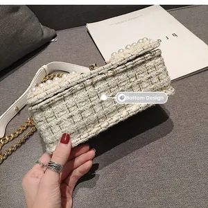 Vue détaillée du fond plat d'un sac en tweed blanc avec chaîne et perles élégantes