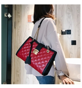 Détail du sac à bandoulière rouge matelassé avec bordure noire et chaîne dorée