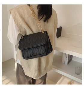 Side view of black V-quilted shoulder bag with elegant gold chain strap on model