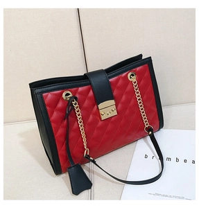 Détail d'un sac matelassé rouge avec chaîne et fermoir doré sur un canapé beige
