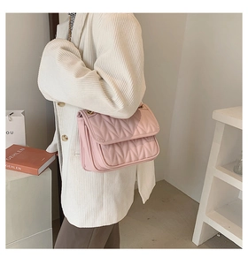 Detail of light pink quilted crossbody bag with gold chain strap on model