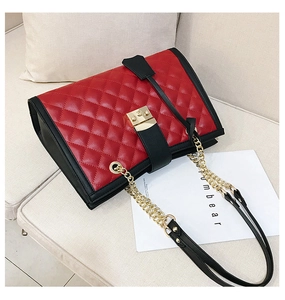 Détail du sac en cuir matelassé rouge et noir avec chaîne dorée et fermoir en métal