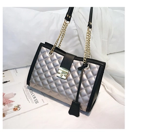 Détail du sac matelassé argenté avec fermoir métallique et finitions en cuir noir