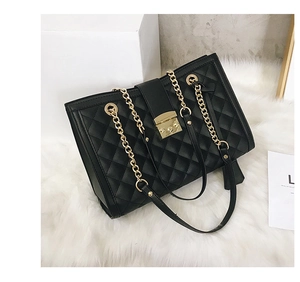 Détail d'un sac à main noir matelassé avec bandoulière chaîne dorée et fermoir en métal