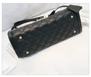Détail du fond d'un sac noir matelassé avec quatre pieds en métal doré de protection