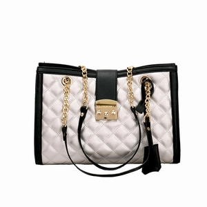 Détail de la texture matelassée argentée et de la chaîne dorée sur un sac à main bicolore
