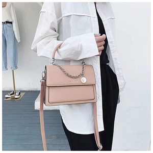 Vue détaillée du sac bandoulière beige avec pendentif chaîne argentée et poignée