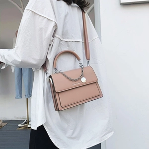 Sac à bandoulière carré rose poudré avec chaîne argentée et poignée porté par mannequin