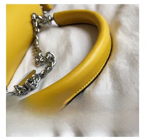 Détail du sac à main en cuir jaune avec grosse chaîne argentée et anneaux métalliques
