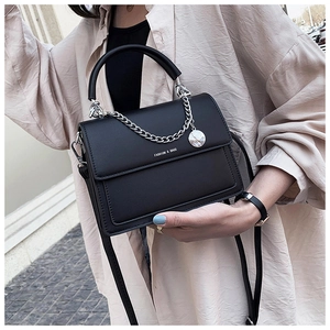 Sac bandoulière tendance en cuir noir avec chaîne argentée sur un mannequin femme