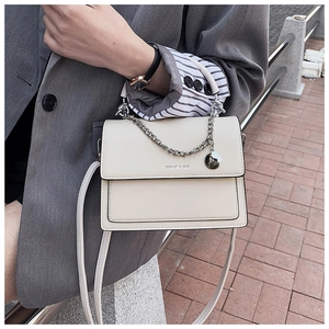 Détail du sac à bandoulière carré blanc cassé avec chaîne argentée et texte mode