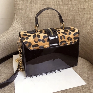 Modische Umhängetasche mit Leopardenmuster, schwarzem Lackleder und Goldkette auf Sofa