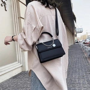 Sac bandoulière noir structuré avec chaîne argentée et logo mode en cuir mat