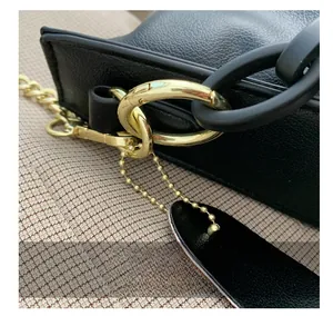 Close-up of black lychee grain leather bag with gold buckle and chunky matte chain detail