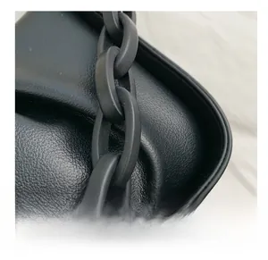 Detail of black lychee grain leather handbag with chunky matte acrylic chain link strap