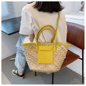Detail of hand-woven straw tote with yellow leather pocket and round metal handles