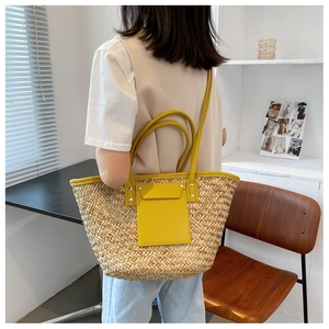 Detail of woven straw tote bag with yellow leather pockets and metal rivet accents