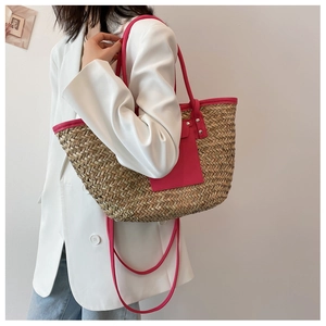 Detail of woven straw tote bag featuring bright pink handles and front pocket detail