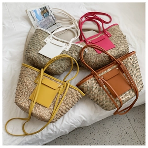 Detail of woven straw tote bags in four colors with leather shoulder straps for beach trips