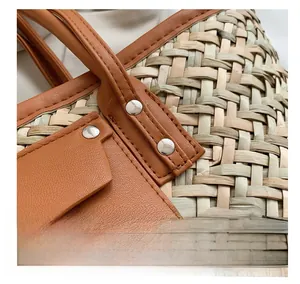 Macro view of woven straw bag detail featuring leather handles and silver metal rivets