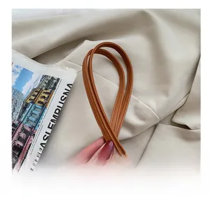 Detail of caramel brown leather shoulder strap with refined tonal stitching on a handbag