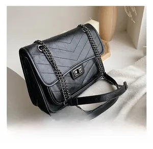Detail of black V-quilted PU leather bag with metallic chain strap and turn-lock closure