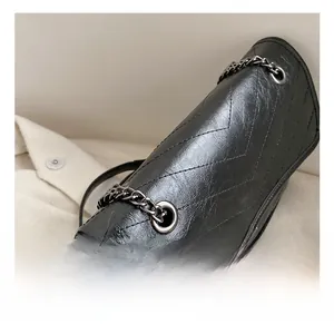 Close-up of black V-quilted faux leather shoulder bag with silver metal chain and eyelets