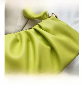 Detailed close-up of lime green pleated cloud bag with textured leather and gold buckle