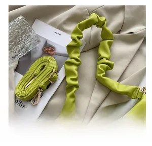 Detail of lime green scrunchie strap and adjustable crossbody strap with gold metal buckle