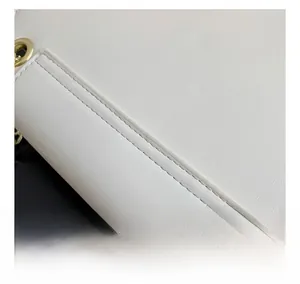 Close-up of white leather handbag showing fine stitching and golden metal eyelet detail