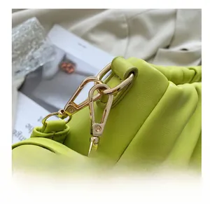 Detailed close-up of the bright green pleated bag with premium gold hardware hooks