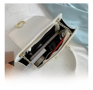 Detail view of the spacious white chain bag interior with multiple compartments and gold hardware