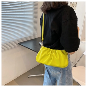 Macro detail of the bright yellow pleated cloud bag texture and slim leather shoulder strap
