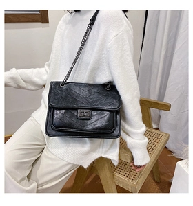 Close-up of black chevron quilted leather bag with silver chain and metal twist lock