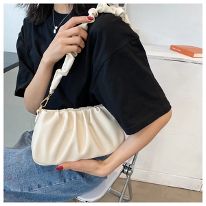 Detailed view of the pleated faux leather texture and golden metal clasp on a beige bag