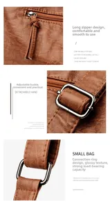 Detail of brown litchi textured leather bag with adjustable silver buckle and long zipper pull