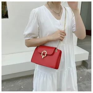 Detail of red crossbody bag featuring gold-tone metal lock and fine chain strap