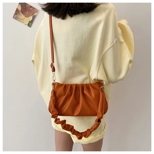 Detailed view of the pleated texture and handle on an orange fashion cloud bag