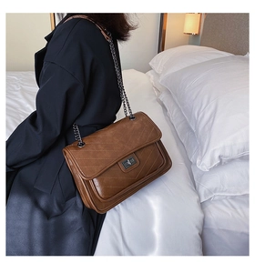 Close-up of caramel chevron quilted shoulder bag with retro chain strap and metal lock