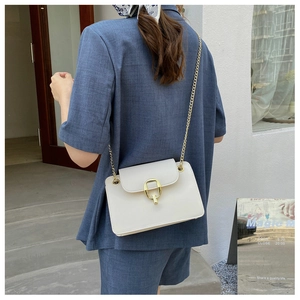 Back view of a woman wearing a white leather crossbody bag with a gold chain strap