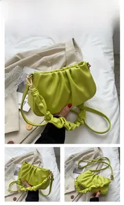 Close-up of kiwi green pleated cloud bag texture with adjustable strap and top handle