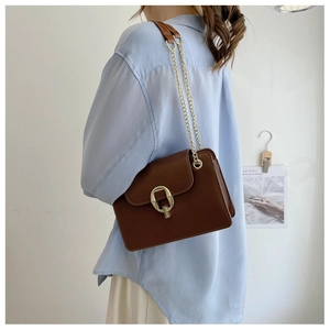 Detailed side view of brown crossbody bag with gold square buckle and chain strap