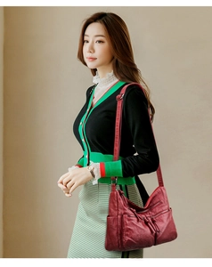 Detail view of burgundy soft leather crossbody bag with multiple zipper pockets on model