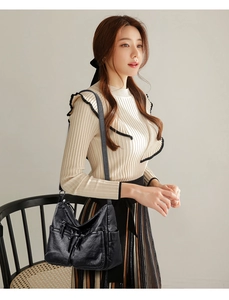 Detail of black soft leather multi-pocket shoulder bag with functional zippers