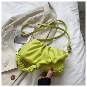 Detail of neon green pleated cloud bag with scrunchie handle on white fabric